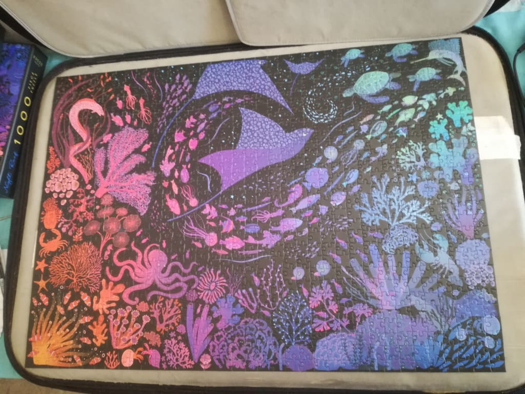 An illustration of a vibrant coral reef at night with stingrays, turtles, and sea creatures in a gradient of colors.