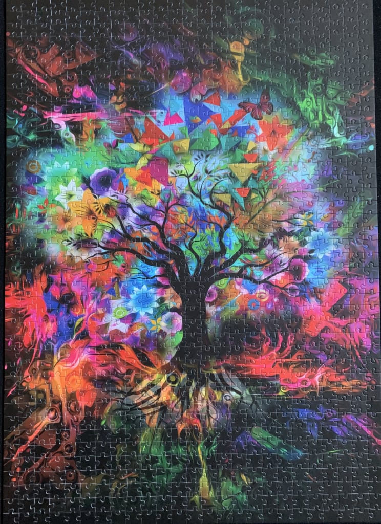Abstract surrealist tree silhouette against a vibrant, kaleidoscopic explosion of colourful flowers and geometric shapes.