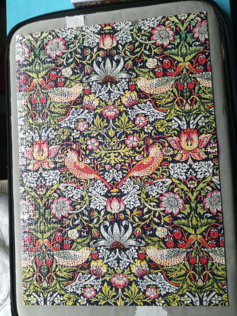 A floral and bird patterned tapestry design in the style of William Morris with vibrant red, green, and cream colors.