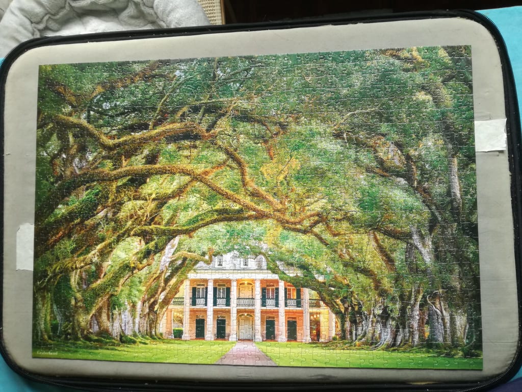 An antebellum mansion framed by a majestic canopy of massive, moss-draped live oak trees.