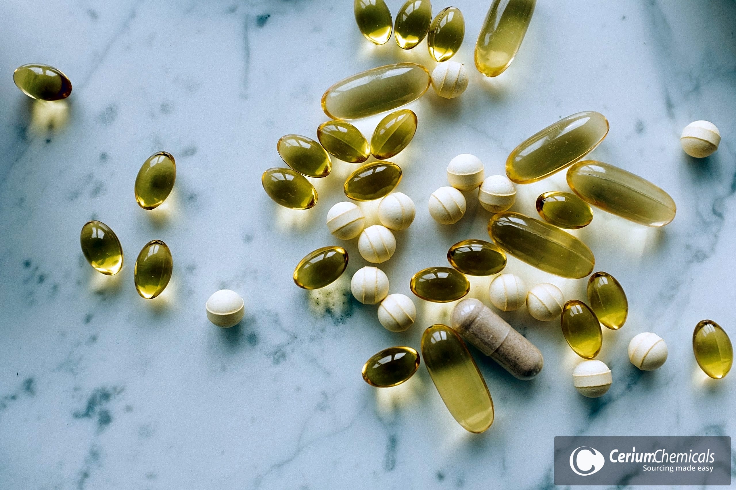 Assorted capsules and tablets scattered across a white marble surface.