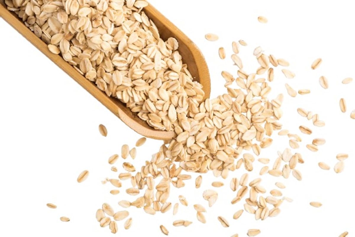 Rolled oats spilling from a wooden scoop