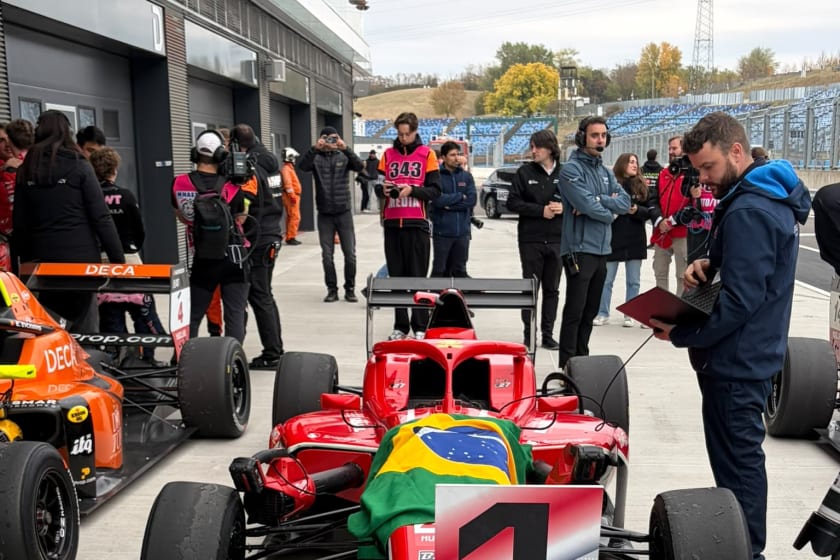 Car 27 in parc fermé under the Brazilian flag, beside the number one board