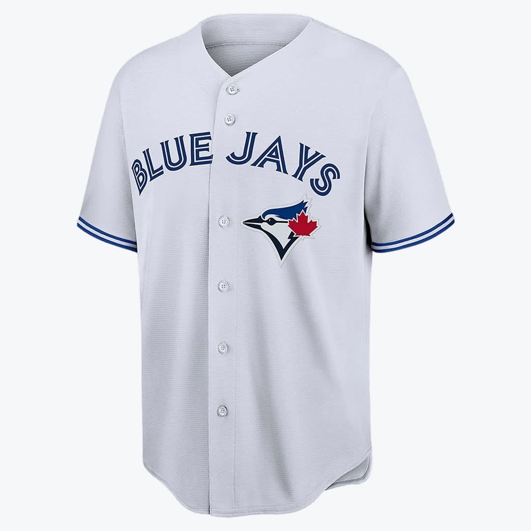 Toronto Blue Jays Grey Baseball Jersey A light grey Toronto Blue Jays baseball jersey with BLUE JAYS written in blue across the chest and the teams blue jay logo on the left.
