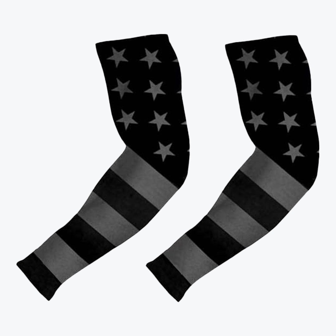 Black and Grey American Flag Athletic Arm Sleeves A pair of athletic compression arm sleeves with a black and grey American flag pattern, featuring stars on the upper half and stripes on the lower half, set against a white background.