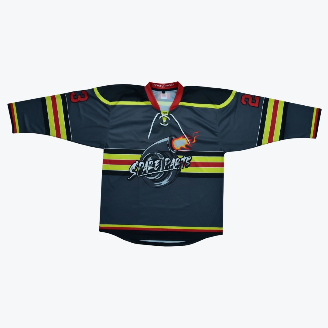 Spare Parts Custom Hockey Jersey A dark grey hockey jersey with a red lace-up collar, yellow and red stripes, and a central logo of a flaming turbocharger with the text SPARE PARTS.