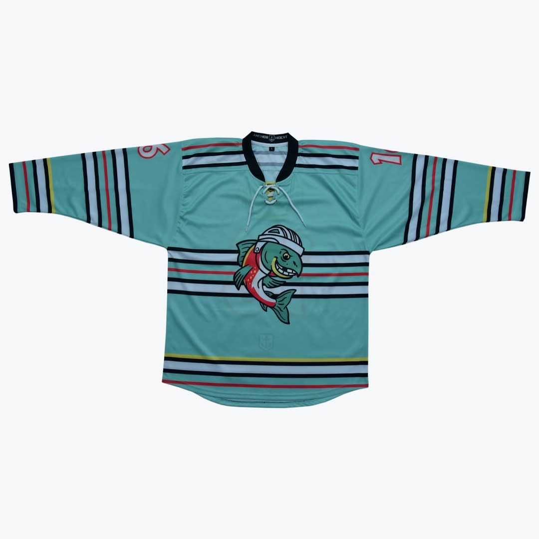 Teal Hockey Jersey with Cartoon Fish Logo A mint green hockey jersey with a cartoon fish logo wearing a helmet, featuring multi-colored stripes and a lace-up neck.