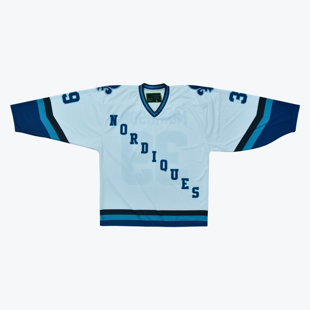 White Quebec Nordiques Concept Hockey Jersey A white hockey jersey with NORDIQUES written diagonally in blue letters, featuring blue and teal stripes and fleur-de-lis shoulder patches.