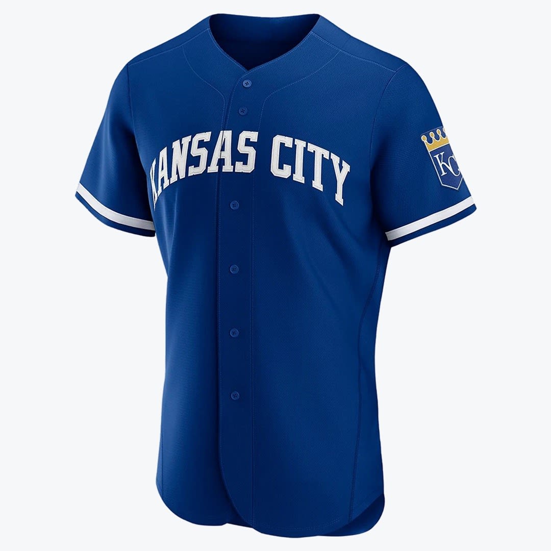 Kansas City Royals Blue Baseball Jersey A royal blue button-up baseball jersey with KANSAS CITY in white arched letters across the chest and the KC crown logo on the left sleeve.