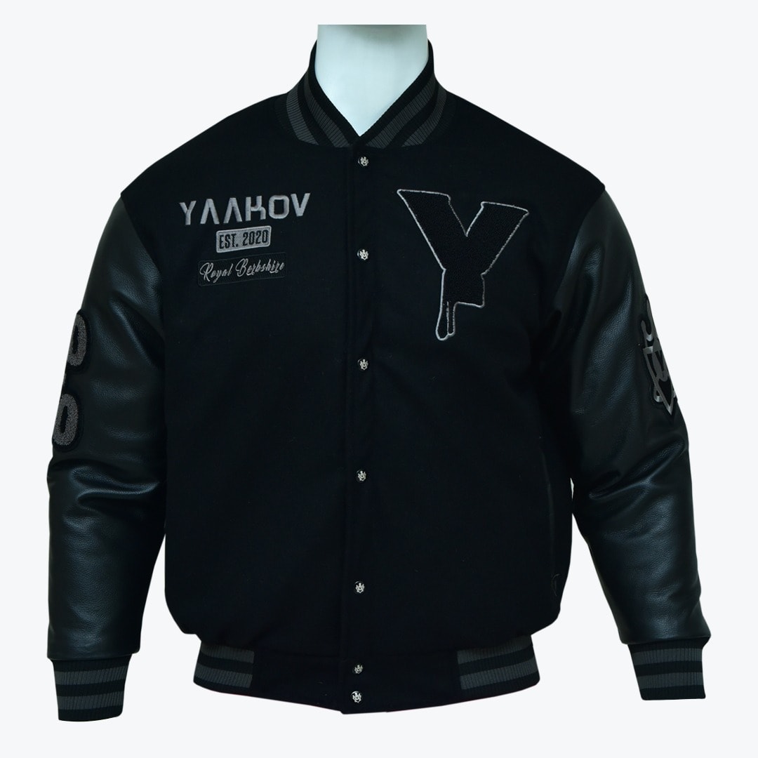Black Yaakov Varsity Jacket A black varsity jacket with leather sleeves, featuring a dripping Y patch and YAAKOV embroidery on a white mannequin.