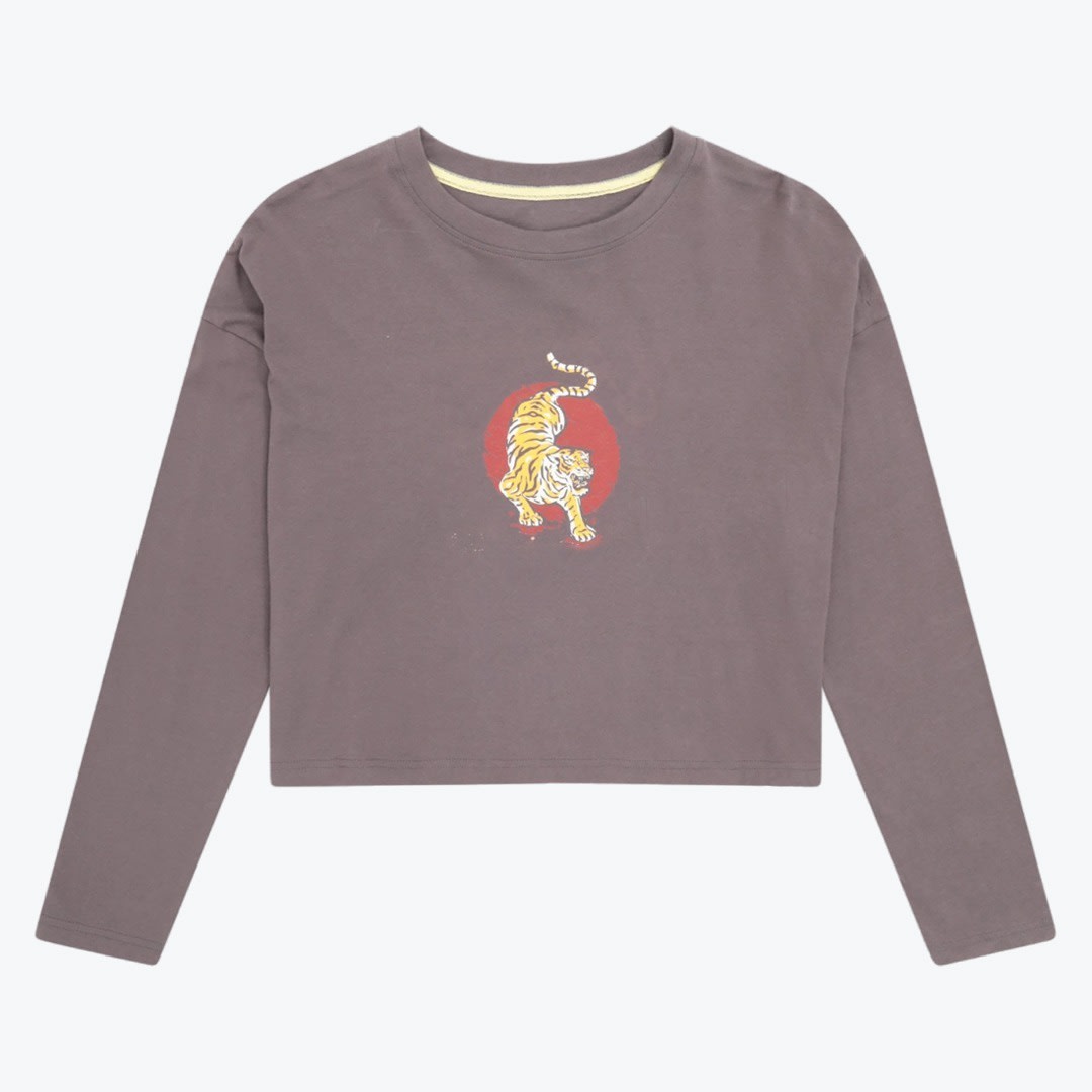 Long-Sleeved Cropped Tiger Graphic T-Shirt A long-sleeved cropped t-shirt in muted purple-grey with a central graphic of a yellow tiger on a red circular background, shown flat against a white backdrop.