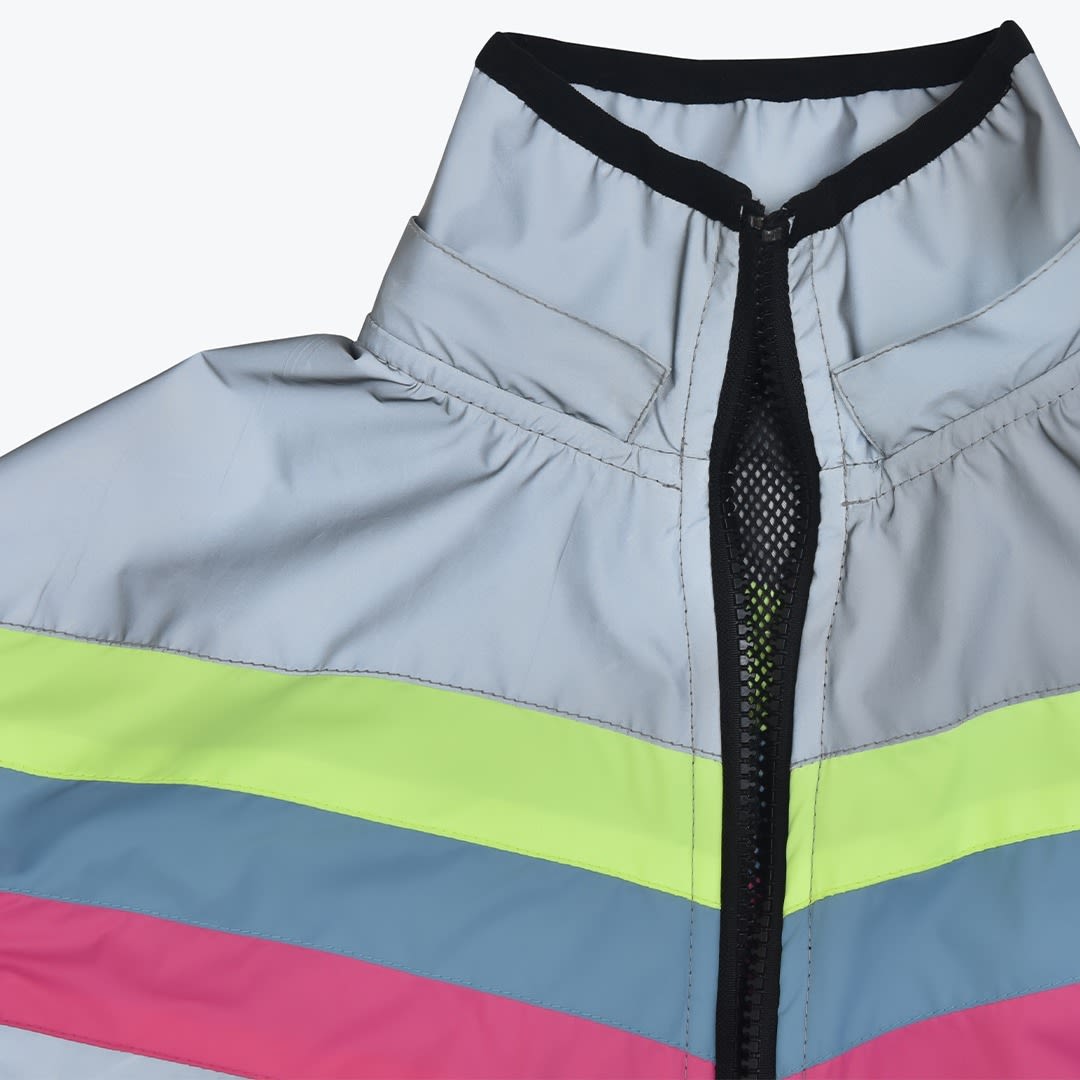 Close-up of a reflective silver jacket featuring a high collar with black trim, a partially unzipped black zipper, and horizontal stripes of neon yellow, blue, and pink.