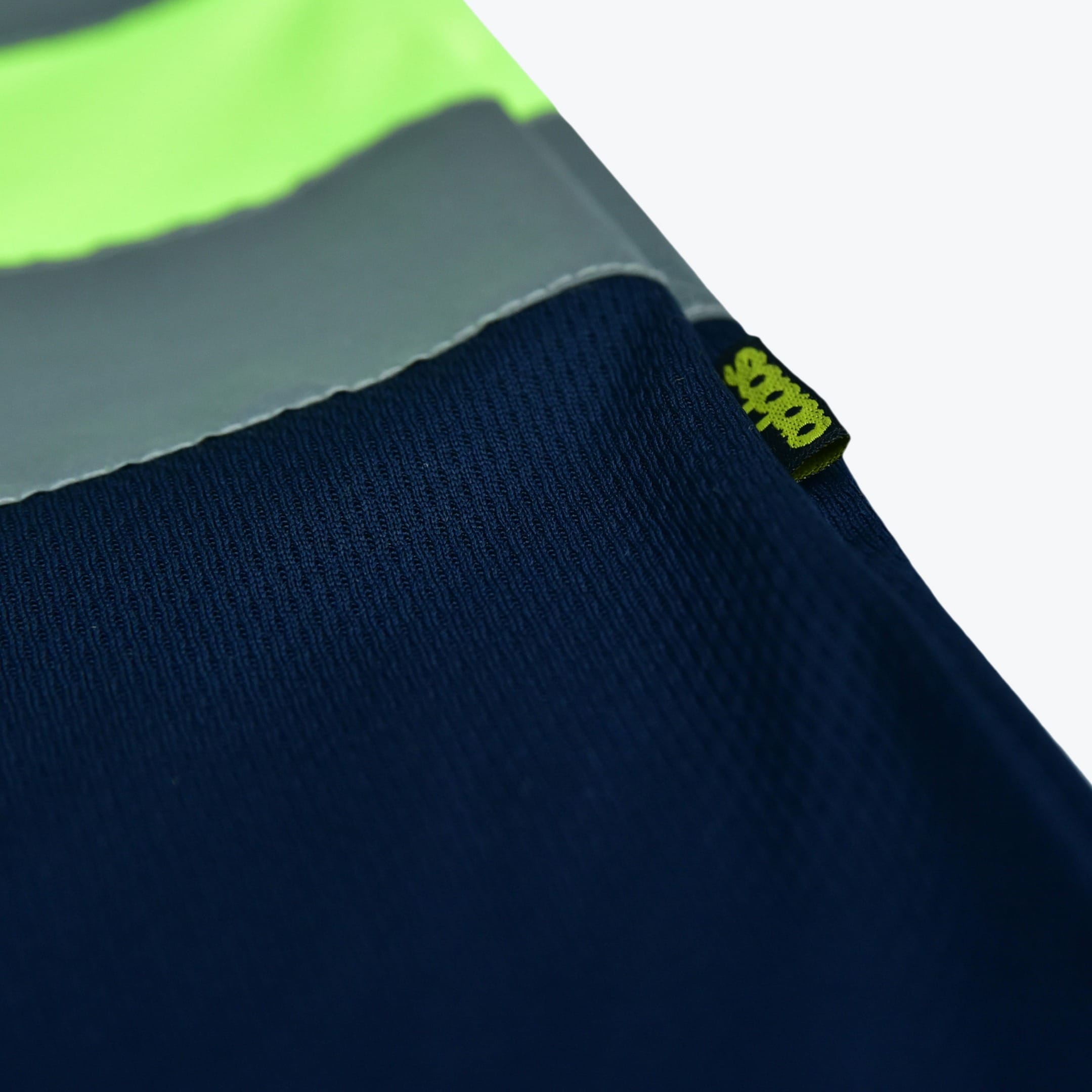 Close-up of navy blue mesh fabric with a grey reflective band, a neon green stripe, and a small black Addos tag.