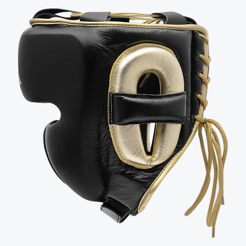 A side-profile view of a black leather boxing headguard with metallic gold padding around the ear, gold trim, and gold laces, set against a plain white background.