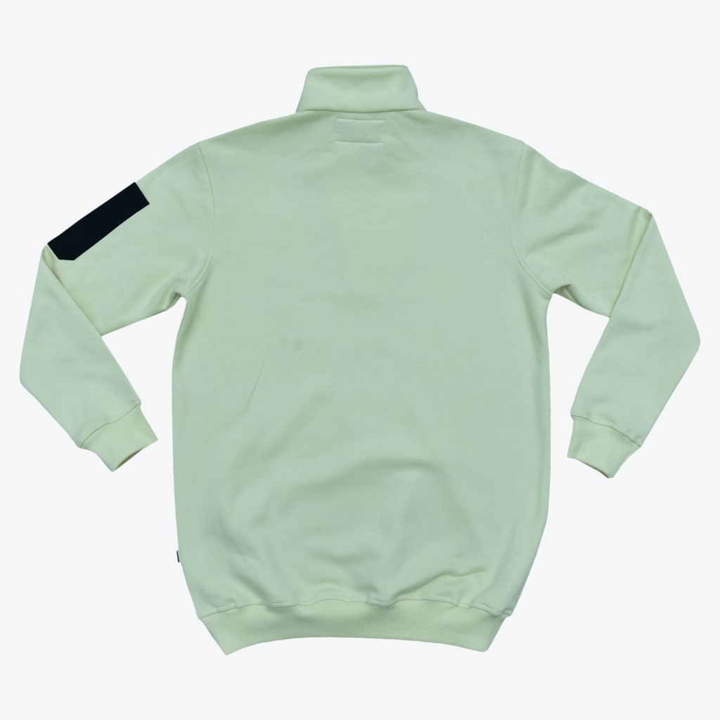 Back view of a pastel mint green zip-up sweatshirt with a black patch on the left sleeve, laid flat on a white background.