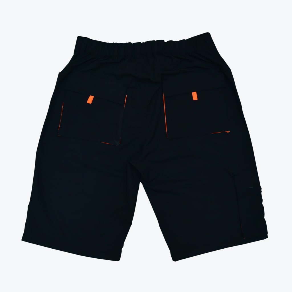 Back view of black cargo shorts with orange accents on the back pockets against a plain white background.