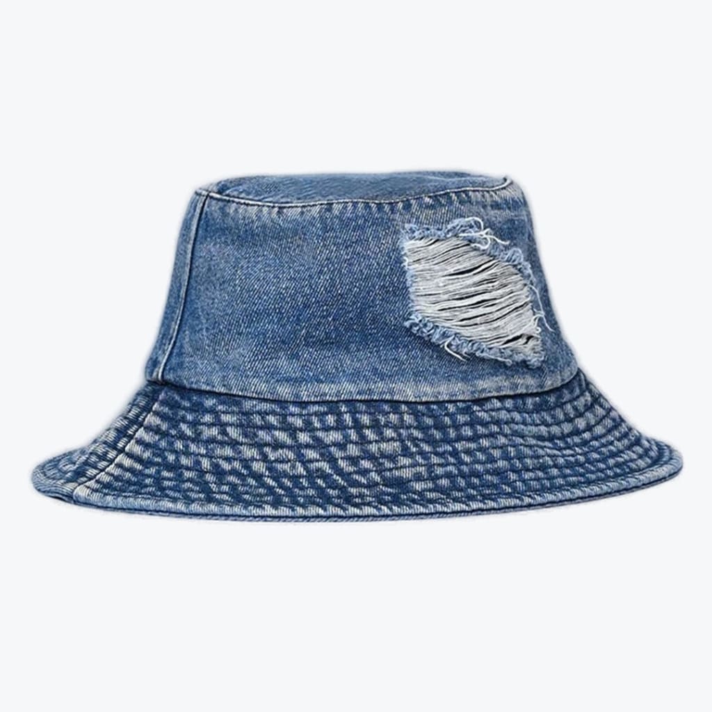 A medium-wash blue denim bucket hat with a ripped, distressed patch on the front side, set against a plain white background.