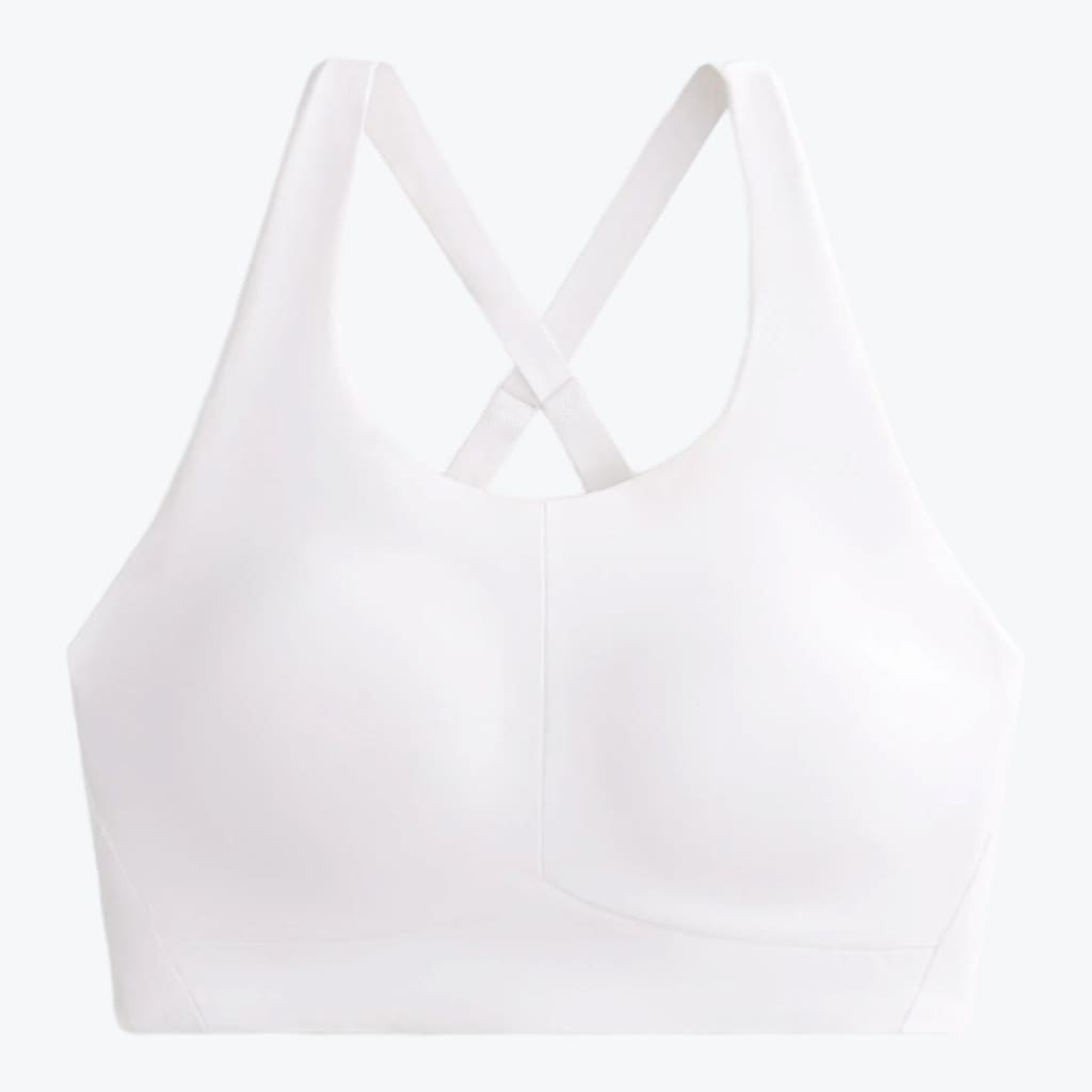 A front-facing studio shot of a solid white sports bra with molded cups and crossed back straps, isolated on a light background.