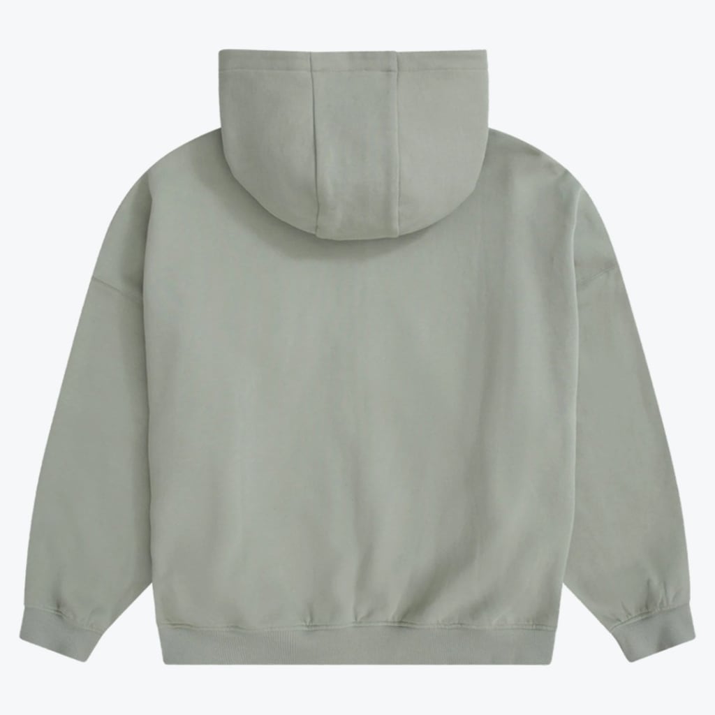 The back view of a plain, light sage green oversized hoodie with a hood, dropped shoulders, and ribbed cuffs and hem, shown on a white background.