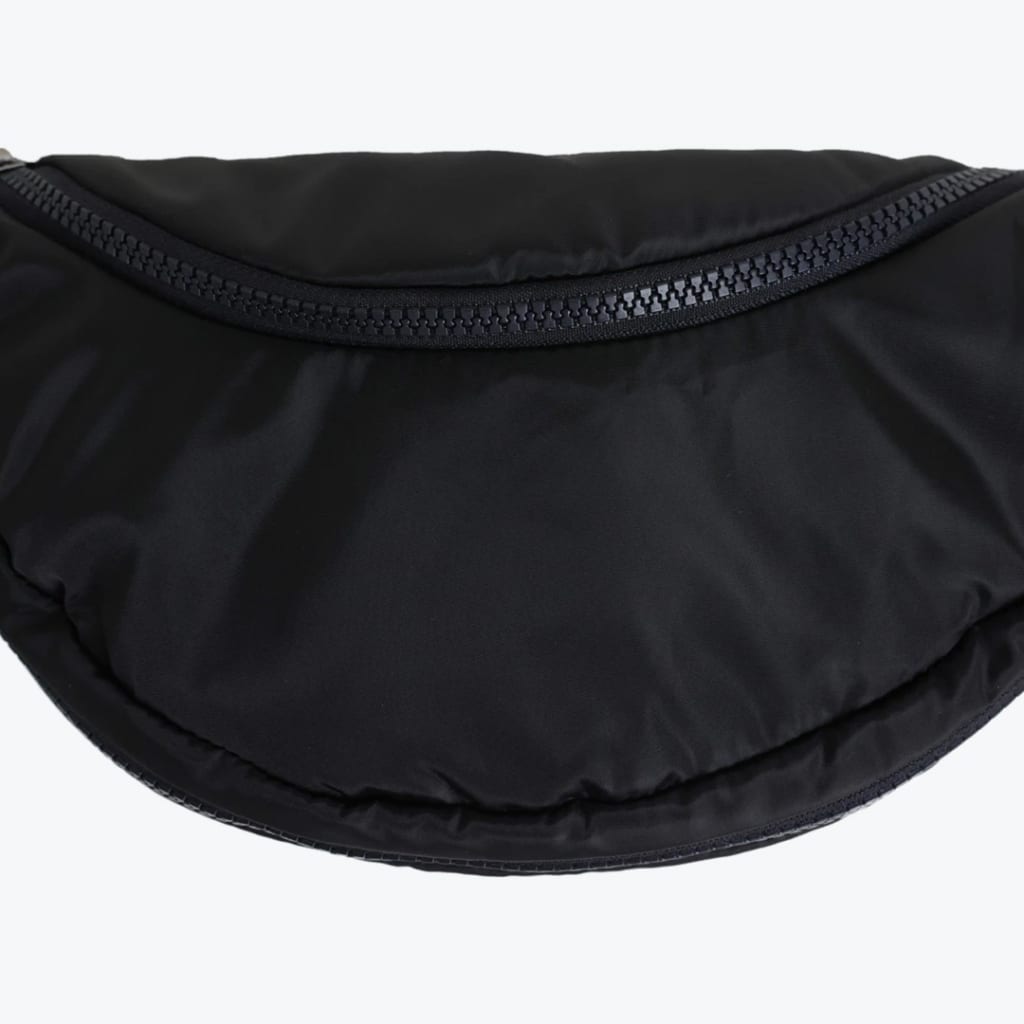 Close-up of a black crescent-shaped nylon waist bag with a chunky black zipper on a white background.