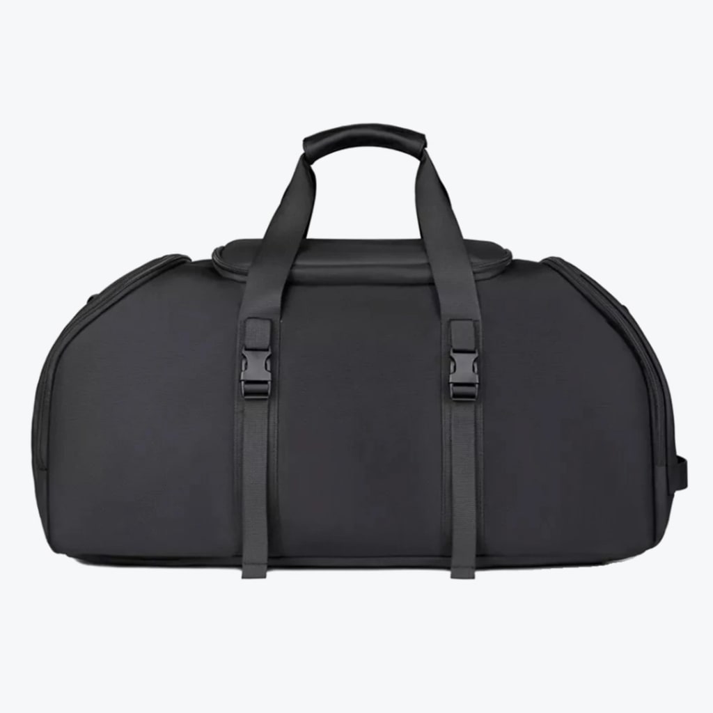 A front view of a structured black duffel bag with two top handles and two vertical buckled straps on a white background.