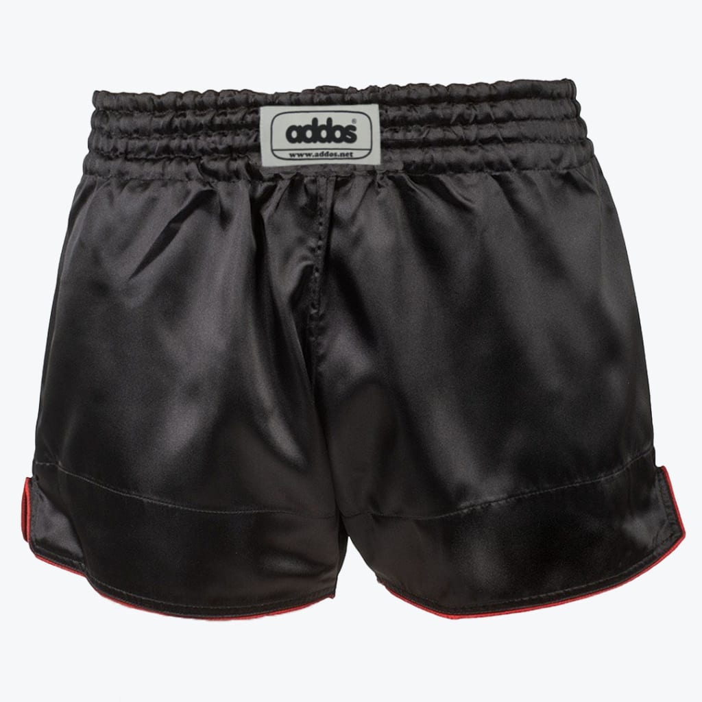 Front view of black satin boxing shorts with a wide elastic waistband, a white logo patch, and red piping along the bottom hem.