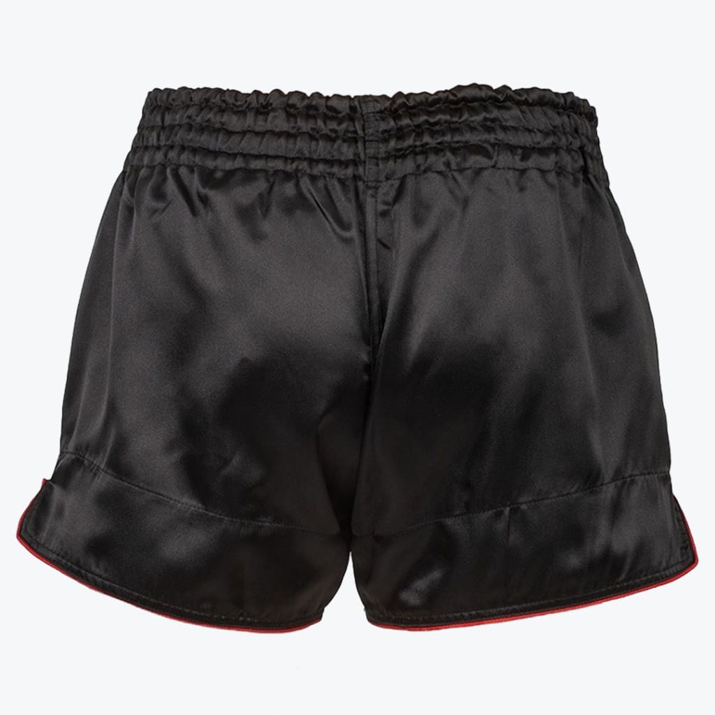 Back view of black satin athletic shorts with an elastic waistband and red trim on the hem.