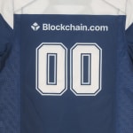 The back of a navy blue sports jersey featuring the number 00 in white block numbers and the Blockchain.com sponsor logo above it.