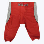 A pair of red football pants with grey side panels and the word WOLVES on the waistband, isolated on a white background.
