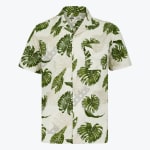 A white short-sleeved button-up shirt with a green monstera leaf pattern, featuring a camp collar and a left chest pocket.