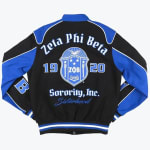 The back of a black and royal blue varsity jacket featuring the Zeta Phi Beta Sorority crest, the text Zeta Phi Beta Sorority, Inc the founding year Sisterhood in blue script.