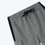 Close-up of grey sweatpants showing the elastic waistband, a tied black drawstring, and a black side stripe on a white background.