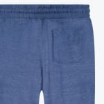 A close-up shot of the back of blue heathered sweatpants showing the elastic waistband and a patch pocket.
