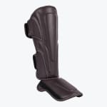 A dark brown leather shin and instep guard with white stitching, displayed against a solid white background.
