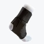 A black ankle brace with adjustable straps worn over a white sock on a model foot, shown from a side-rear angle against a white background.