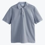 A flat lay of a light blue-grey short-sleeve polo shirt with a two-button collar against a plain white background.