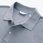 Close-up view of the collar and placket of a light blue-grey textured polo shirt with two white buttons.