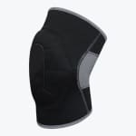 A black knee compression sleeve with a padded front and a grey mesh back panel, shown from a side angle on a white background.