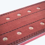 Close-up view of a reddish-brown suede weightlifting belt featuring double-prong holes and black stitching.