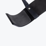 Close-up of the curved elbow support of a black bicep arm blaster, featuring thick foam padding and a nylon strap secured with a silver rivet.