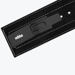 Close-up of a black metal lever buckle with the white addos logo on a black suede weightlifting belt with white stitching.