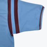 Close-up of a light blue short-sleeve jersey showing claret stripes on the shoulder and claret trim on the cuff.