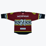 The back of a maroon hockey jersey with the name MCKEWAN and number 71. It features a prominent black-and-white cow print stripe across the middle and on the sleeves, a Canadian flag at the collar, and a The Keg sponsor logo near the hem.