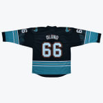 Back view of a black hockey jersey with OLUND and 66 in white and orange, featuring teal accents and Vancouver Grizzlies shoulder patches.