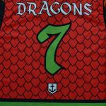 The back of a red jersey with a dragon scale pattern, featuring the word DRAGONS in a white fantasy font and a large green number 7.