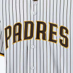 Close-up of a white San Diego Padres pinstripe baseball jersey with the word PADRES in brown and gold lettering across the chest.