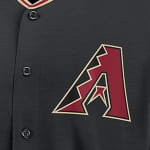 Close-up of a black Arizona Diamondbacks baseball jersey showing the red and gold stylized A logo with a snake tongue design.