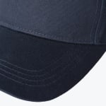 Close-up view of a navy blue baseball cap brim showing stitched curved lines and fabric texture.