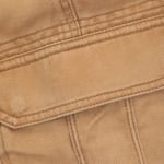 Close-up view of a tan denim jacket pocket flap showing detailed stitching and twill fabric texture.