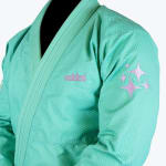Close-up of a mint green Addos Jiu-Jitsu gi jacket with purple embroidered logo and star designs on the sleeve.